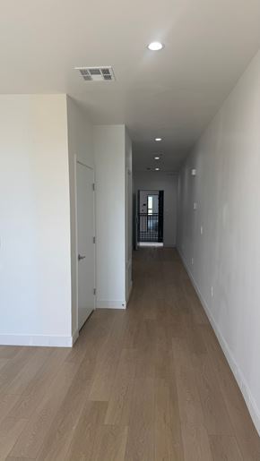 Inglewood apartment for rent - A long hallway with a door on the left and a window on the right.