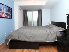 Toronto apartment for rent - A bedroom with a bed, nightstand, and a painting on the wall.