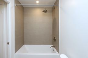 Toronto apartment for rent - A white bathtub is in a small bathroom with a shower head.