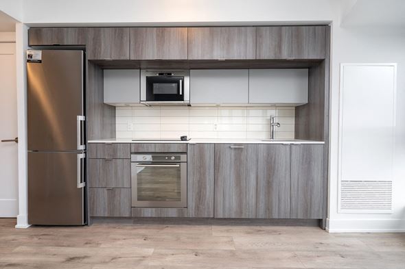 Toronto apartment for rent - A modern kitchen with a stainless steel refrigerator and a microwave above the oven.