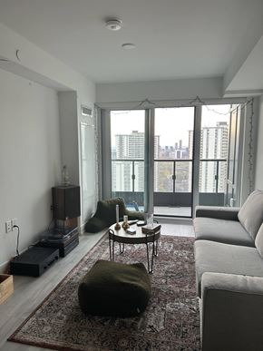 Toronto apartment for rent - A living room with a grey couch, a coffee table, and a large window with a view of the city.
