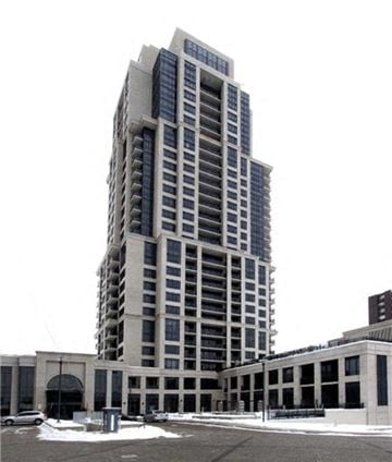 Etobicoke apartment for rent - A tall building with many windows is in the foreground with a white sky in the background.