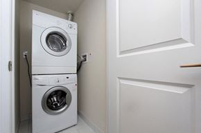 Etobicoke apartment for rent - A white dryer and washer are stacked on top of each other in a small laundry room.