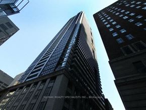 Toronto apartment for rent - A tall building with a glass facade stands between two other buildings.