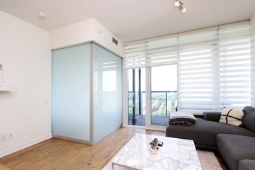 Toronto apartment for rent - A modern living room with a grey couch and a glass door.