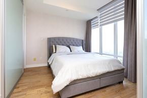 Toronto apartment for rent - A bedroom with a large bed and a window with curtains.