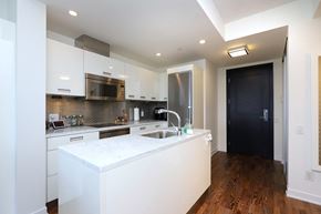 Toronto apartment for rent - A modern kitchen with white cabinets and a wooden floor.
