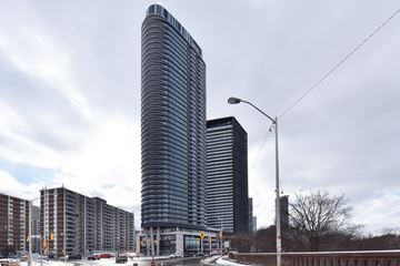 Toronto apartment for rent - A tall, curved building stands in front of a row of shorter buildings.