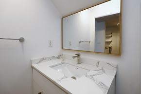 Toronto apartment for rent - A bathroom with a marble countertop and a large mirror.