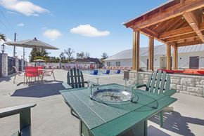 Pensacola apartment for rent - A pool surrounded by red chairs and a striped umbrella.