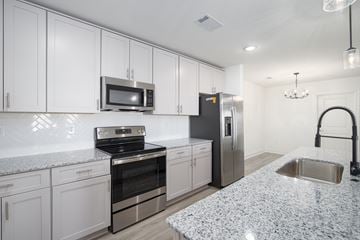 Pensacola apartment for rent - A kitchen with white cabinets and a granite countertop.