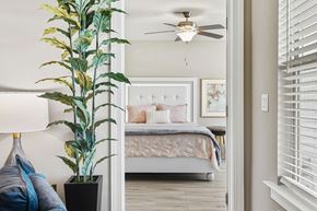 Ocala apartment for rent - A bedroom with a bed, a plant, and a ceiling fan.