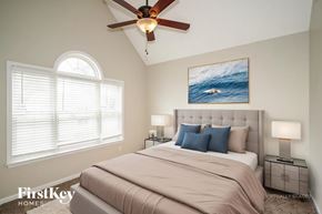 Murfreesboro house for rent - A bedroom with a large bed, a ceiling fan, and a painting of a wave on the wall.