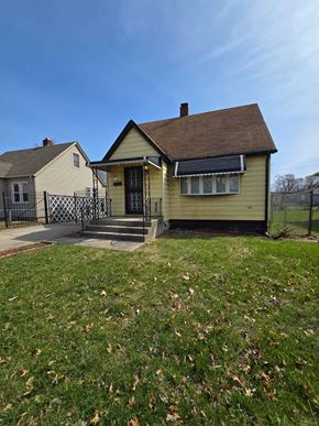 Gary house for rent - A yellow house with a black gate in front.