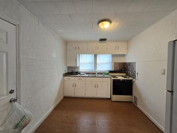 Gary house for rent - A kitchen with white cabinets and a wooden floor.
