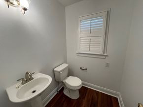 Wilson house for rent - A white bathroom with a toilet, sink, and window.