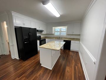 Wilson house for rent - A kitchen with black appliances and white cabinets.