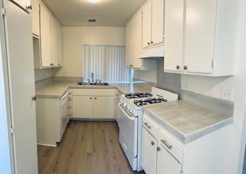Fullerton apartment for rent - A kitchen with white cabinets and a stove top oven.