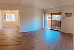 Fullerton apartment for rent - A room with wooden floors and a sliding glass door leading to a balcony.