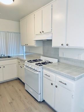 Fullerton apartment for rent - A white kitchen with a stove and cabinets.