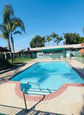 Tustin apartment for rent - A pool surrounded by a fence and palm trees.