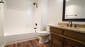 Forney house for rent - A white toilet sits in a bathroom next to a bathtub.
