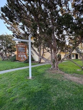 Orange apartment for rent - A sign for Olliwood Estates is in front of a tree.
