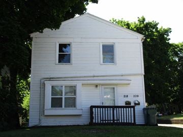 East Lansing house for rent - A white house with a black fence and a mailbox on the front.