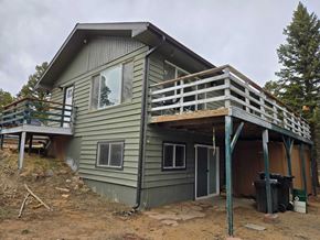 Woodland Park house for rent - A house under construction with a grey exterior and a wooden deck.