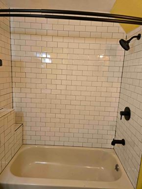Woodland Park house for rent - A white tiled shower with a black handle and a white bathtub.