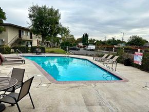 Anaheim apartment for rent - A pool surrounded by a concrete patio and a black metal fence.
