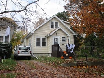 Lansing house for rent - A house with a car parked in front of it and a jack-o-lantern on the porch.