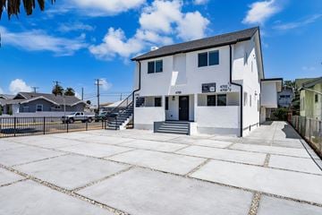 Los Angeles apartment for rent - A white building with a black roof and a sign that reads "4700 12" is surrounded by a paved lot.