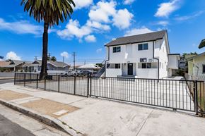 Los Angeles apartment for rent - A white house with a black fence and a palm tree in front.