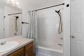 Evans house for rent - A white bathroom with a sink, mirror, and bathtub.
