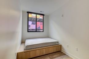 Columbus apartment for rent - A bedroom with a bed and a window with a colorful abstract painting.