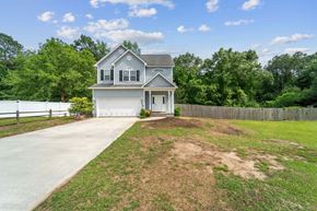 Jacksonville house for rent - A house with a grey roof and white walls is surrounded by a grassy area and a wooden fence.