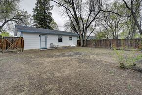Colorado Springs house for rent - A small white house with a brown fence and trees in the background.