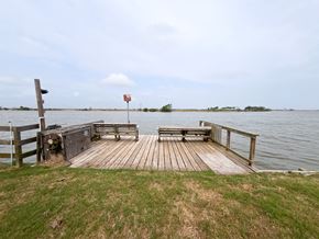 Brazoria house for rent - A wooden dock extends into a body of water with a red flag in the distance.