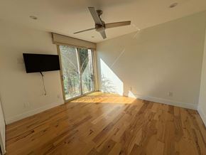 Coronado apartment for rent - A room with a ceiling fan and a flat screen TV mounted on the wall.