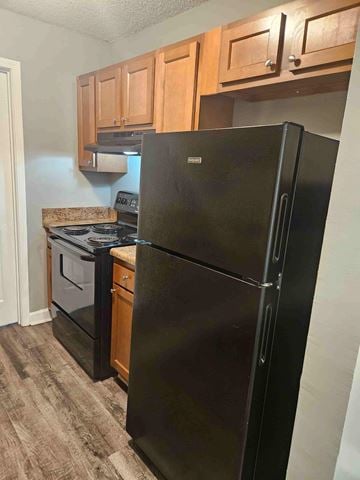 Albany apartment for rent - A black refrigerator in a kitchen with wooden cabinets.