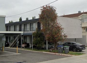 Gardena apartment for rent - A tree with red leaves is in front of a grey building.