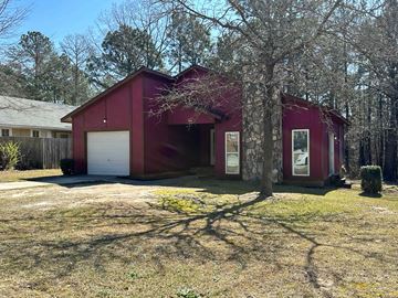 Spring Lake house for rent - A red barn-like building with a white garage door is surrounded by trees.