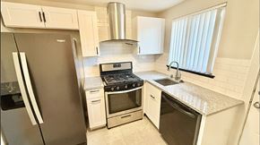 Lakewood apartment for rent - A kitchen with a black refrigerator, white cabinets, and a granite countertop.