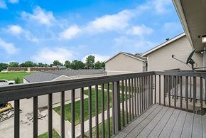Longmont apartment for rent - A balcony with a black railing overlooks a grassy area and other houses.