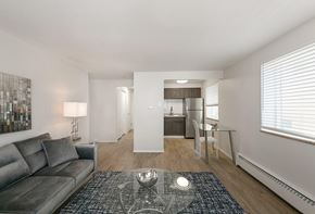 Denver apartment for rent - A modern two-story building with a black awning and a red brick pathway leading to the entrance.