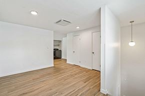 Longmont apartment for rent - A room with white walls and wooden flooring with a black trash can and a light hanging from the ceiling.