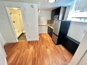 Denver apartment for rent - A kitchen with a refrigerator, microwave, and wooden floors.