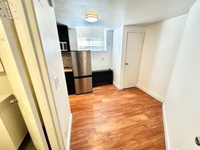Denver apartment for rent - A kitchen with a white fridge and wooden floors.