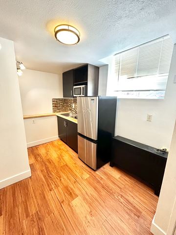 Denver apartment for rent - A kitchen with a black refrigerator and wooden floors.